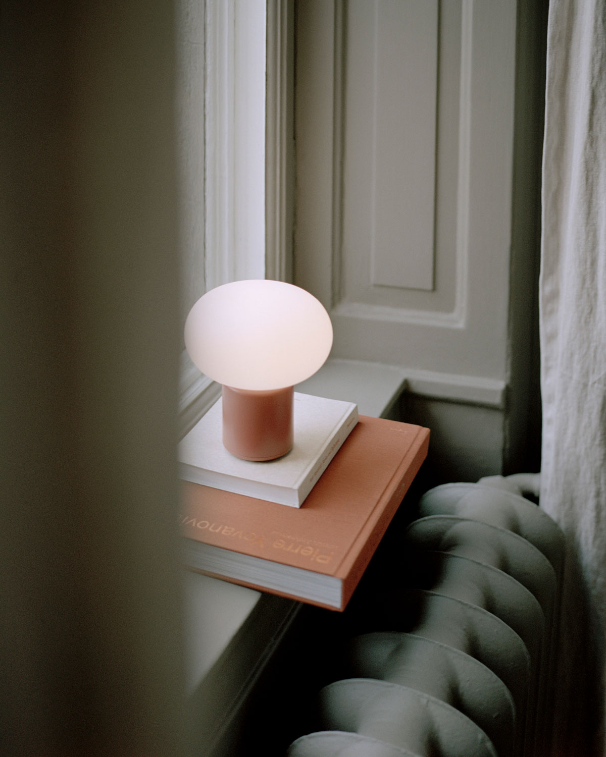 Karl Johan Portabel Bordslampa Earth Red i fönsterkarm på två böcker