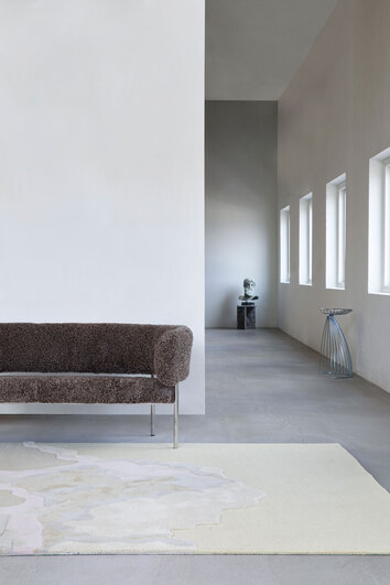 Cloud9 Matta Afternoon framför en soffa i mörkt tyg