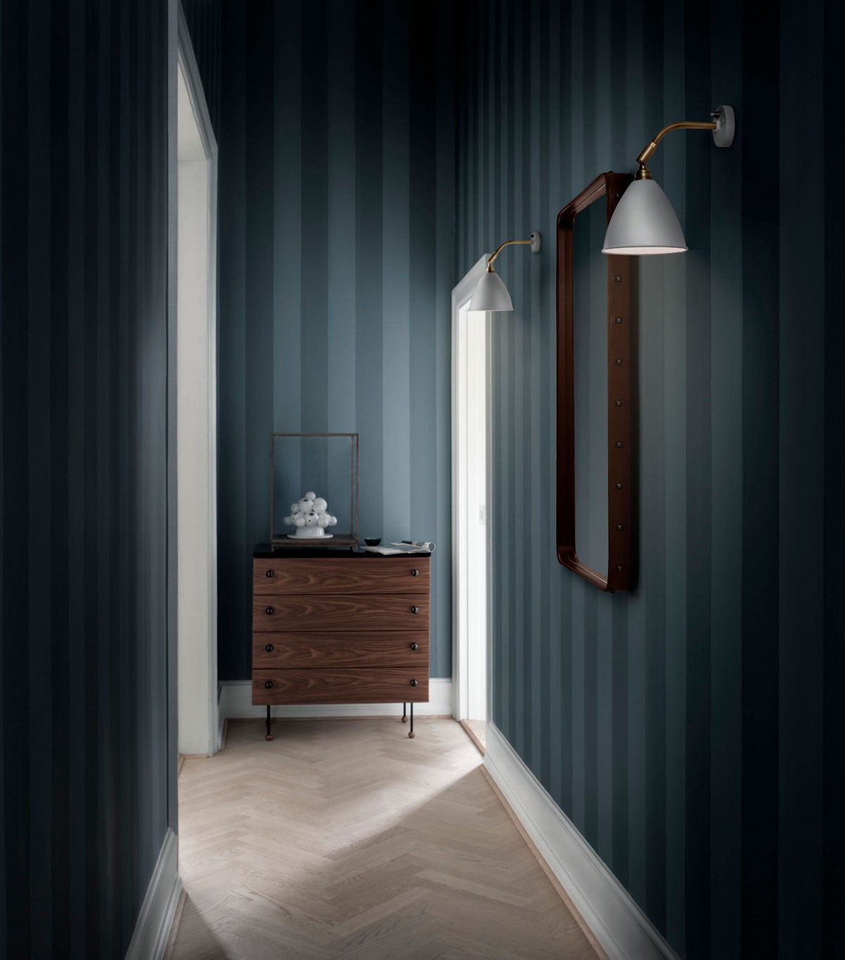 62 Dresser Byrå med fyra lådor står i slutet av en lång hall med blårandiga tapeter. 