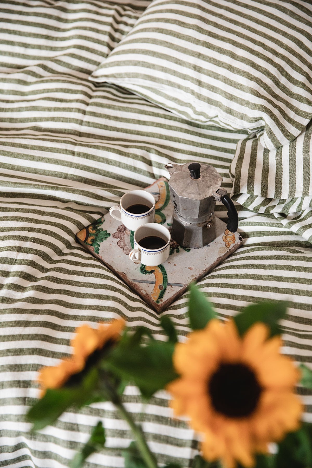 Misty Edge Påslakan 150x210 i färgen Jeep Green med frukostbricka och solrosor i förgrunden