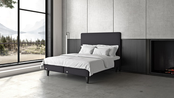 Impression Ramsäng i öppet sovrum med stora fönster som vetter ut mot sjöutsikt