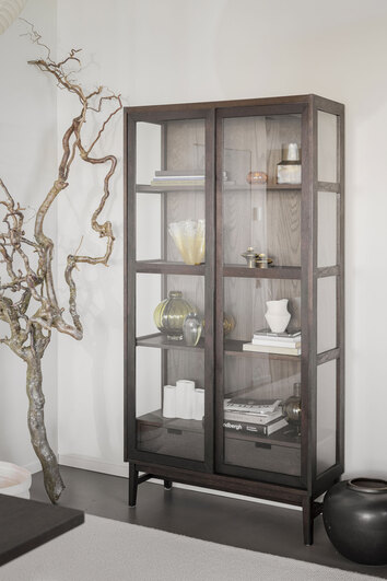 Hazelton Vitrinskåp i brun ek bredvid en stor trädgren som dekoration