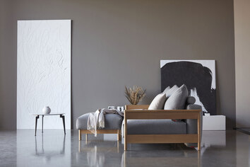 Miljöbild på soffan Malloy Wood, med tillhörande pall. Tyg 533 Bouclé Ash Grey.