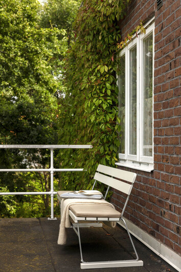 Soffa 5 Vitlackad Ek mot tegelfasad med en sittdyna och filt