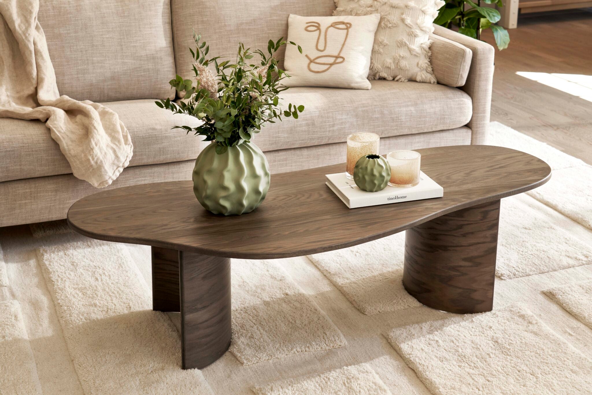 Curve soffbord med en blomvas och ljuslyktor på ståendes i ett vardagsrum. 