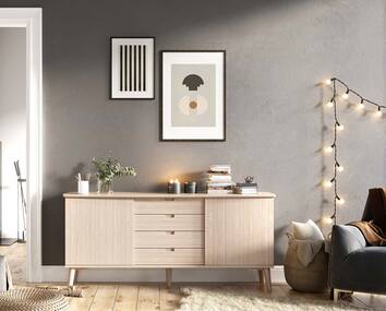 CASØ 120 Skänk mot grå vägg med två tavlor med grafiska motiv