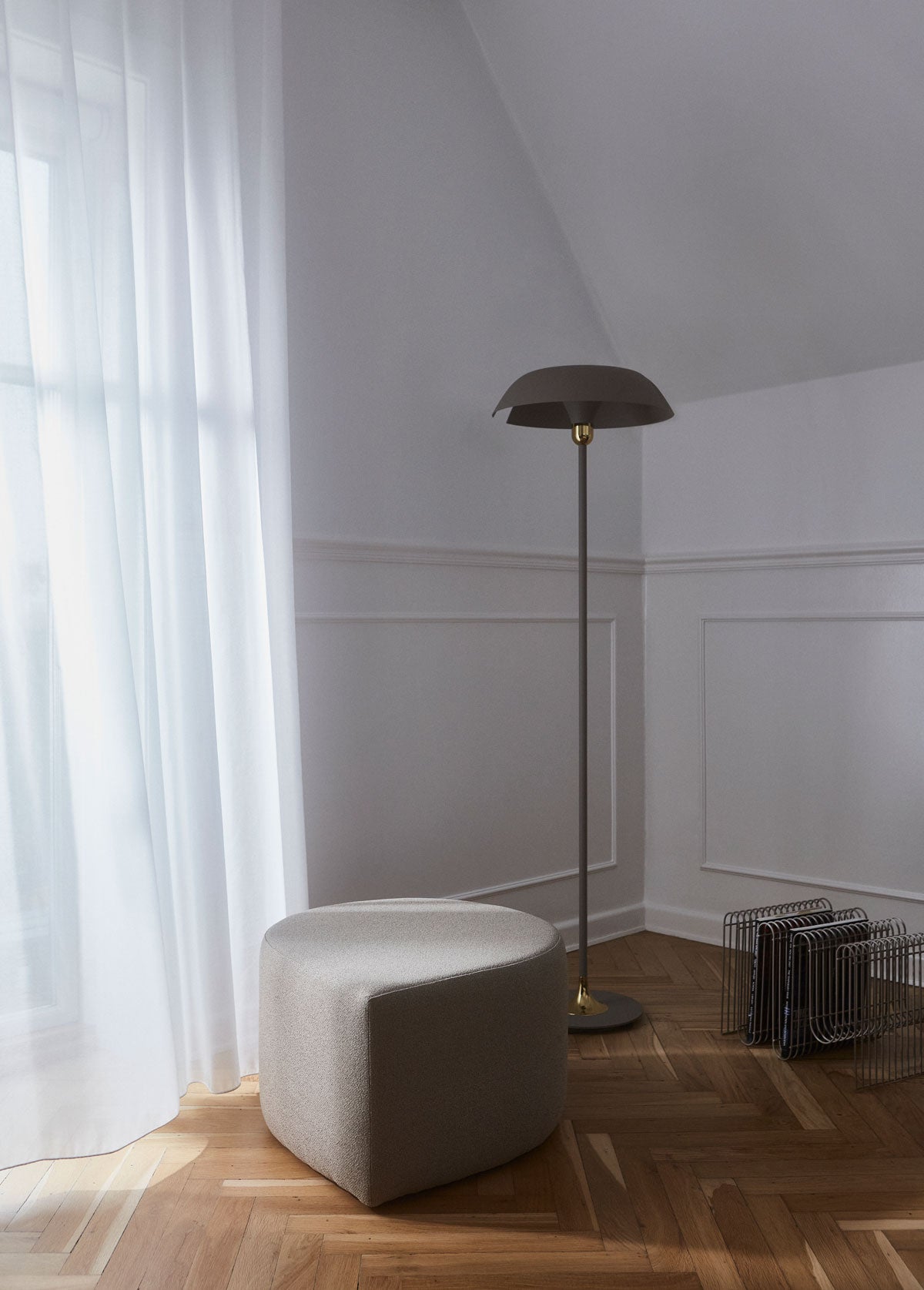 Stilla Puff i Tyg Taupe Bouclé vid fönster med skira gardiner och en golvlampa