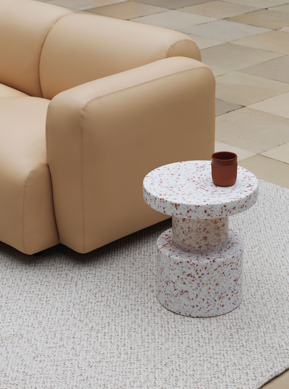 Bit Stool på vävd matta med lädersoffa i bakgrunden