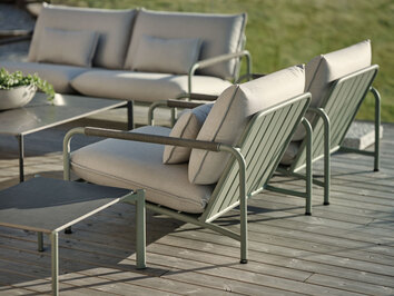 Lerberget Fåtölj i grön färg på soligt trädäck fotograferat bakifrån