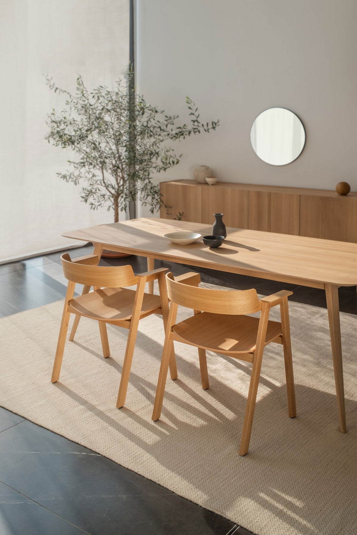 Två stycken Flip Stol i naturlackad ek runt ett rektangulärt matbord i matplats med beige matta