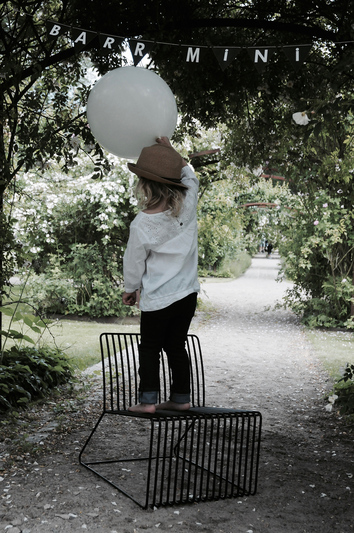 Barr Mini Loungestol Svart med ett barn som håller en ballong under en banderoll med ordet "Mini"