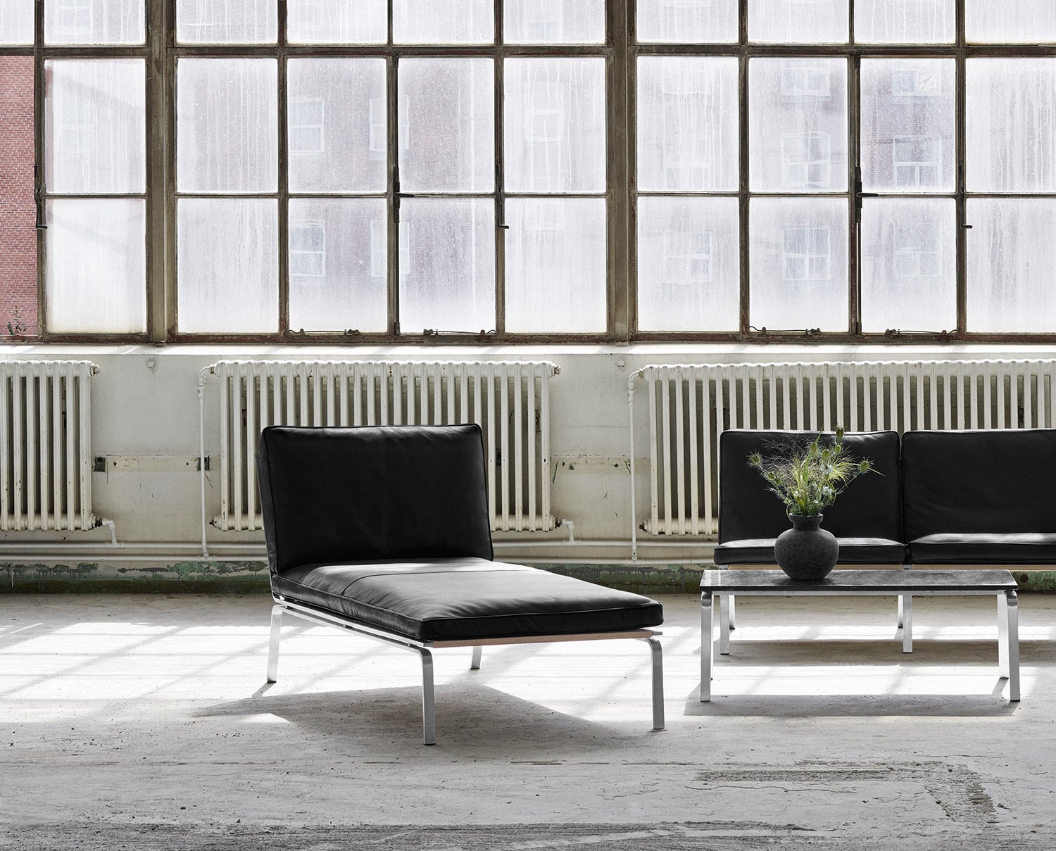 Man Schäslong i industrilokal bredvid ett soffbord med en krukväxt