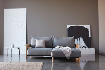 Miljöbild på soffan Malloy Wood, med tillhörande pall. Tyg 533 Bouclé Ash Grey.