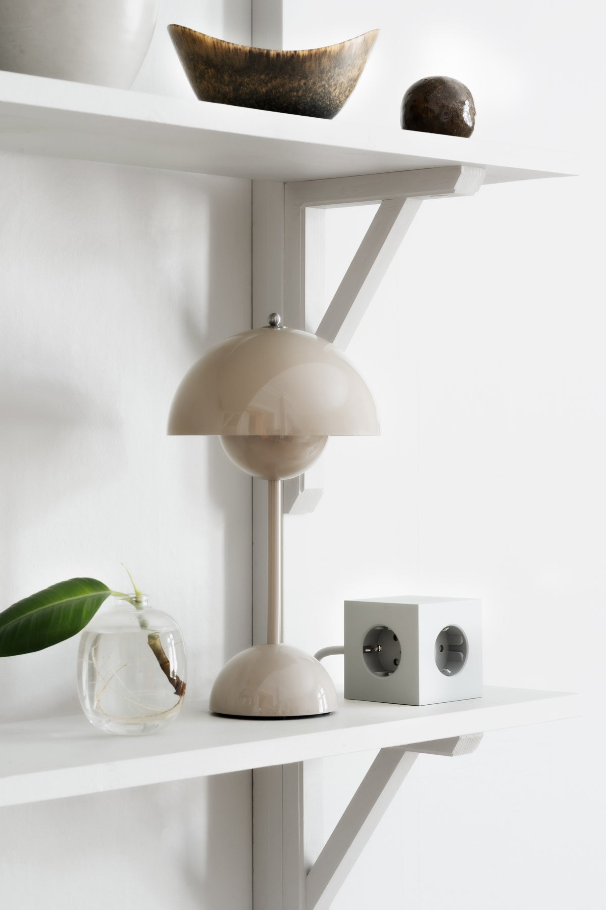 Square 1 Grenuttag Grå på en vägghängd hylla bredvid en beige bordslampa