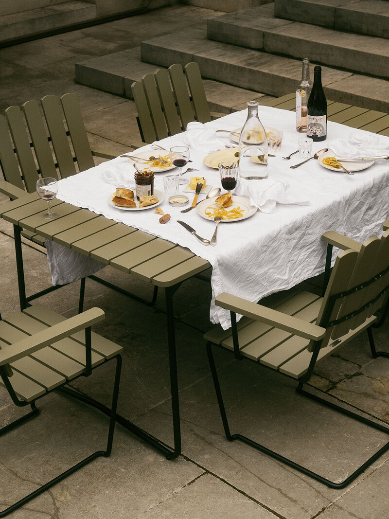 Fåtölj A2 och Bord B31 i ljusgrön lackad ek med svart stativ. Bordet är dukat med vit duk och fransk frukost.