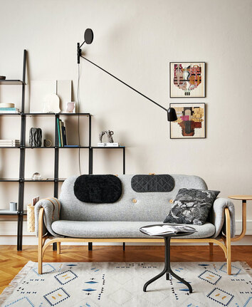 Miljöbild på Button, med kudde i tyg samt kudde i svart fårskinn