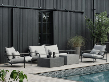 Lerberget Fåtölj och Soffa i grå färg på trädäck framför husfasad