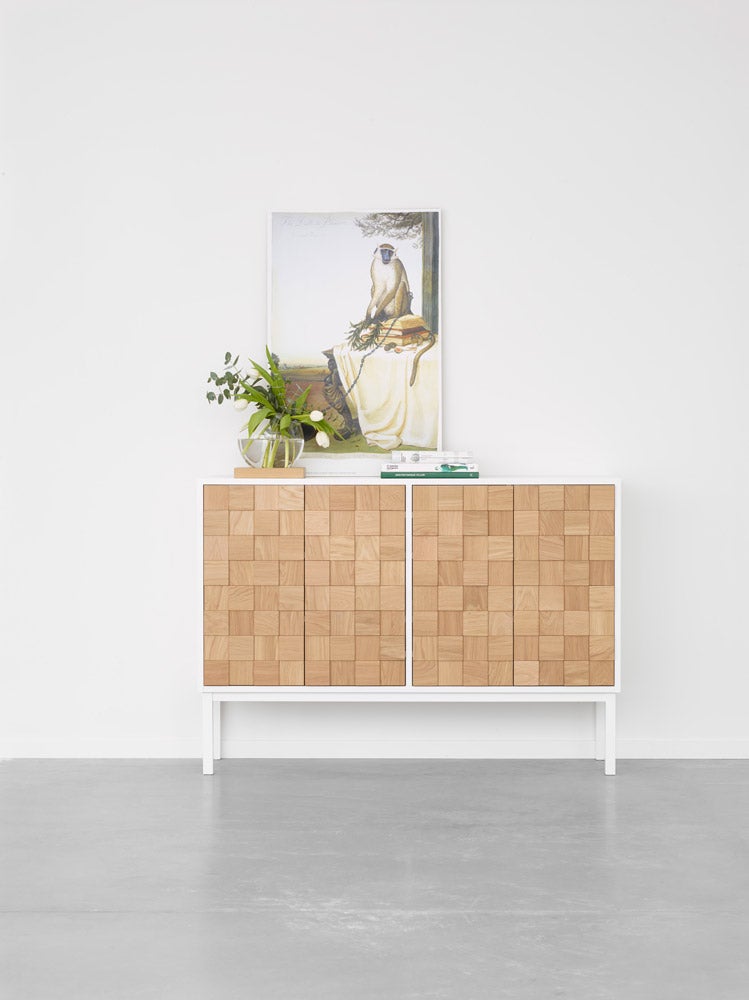 Collect 2016 Skåp Lågt i vitpigmenterad ek. Det står en vas, böcker och en tavla med en apa på skåpet.