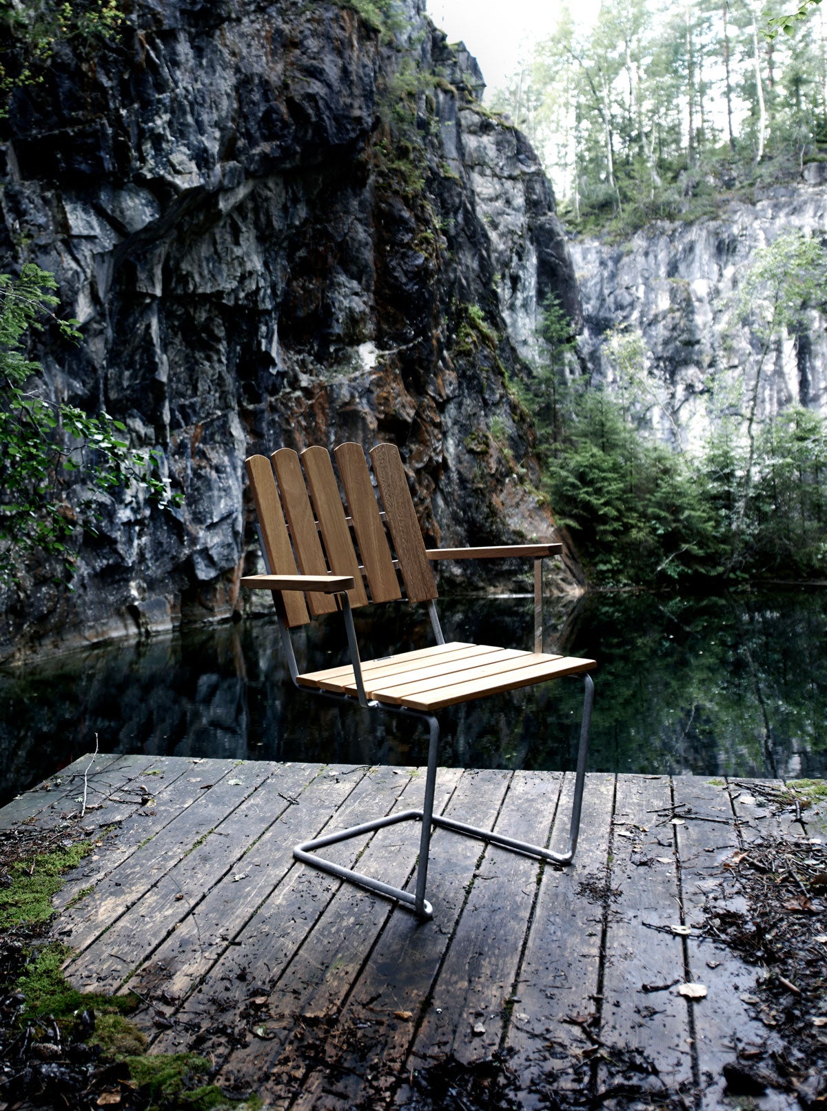 Fåtölj A2 i oljad ek på trädäck med mossig grotta i bakgrunden
