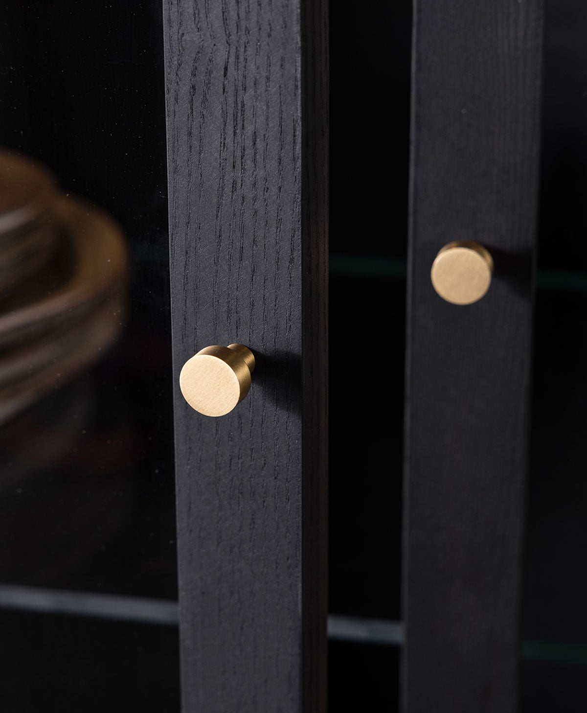 Mässingshandtag på vitrinskåpet Ant, i svartoljad ask (C14). 