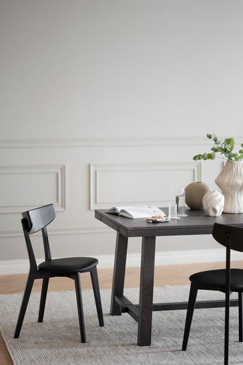 Ami Stol i svartbetsad ask vid ände av rektangulärt matbord på ullmatta