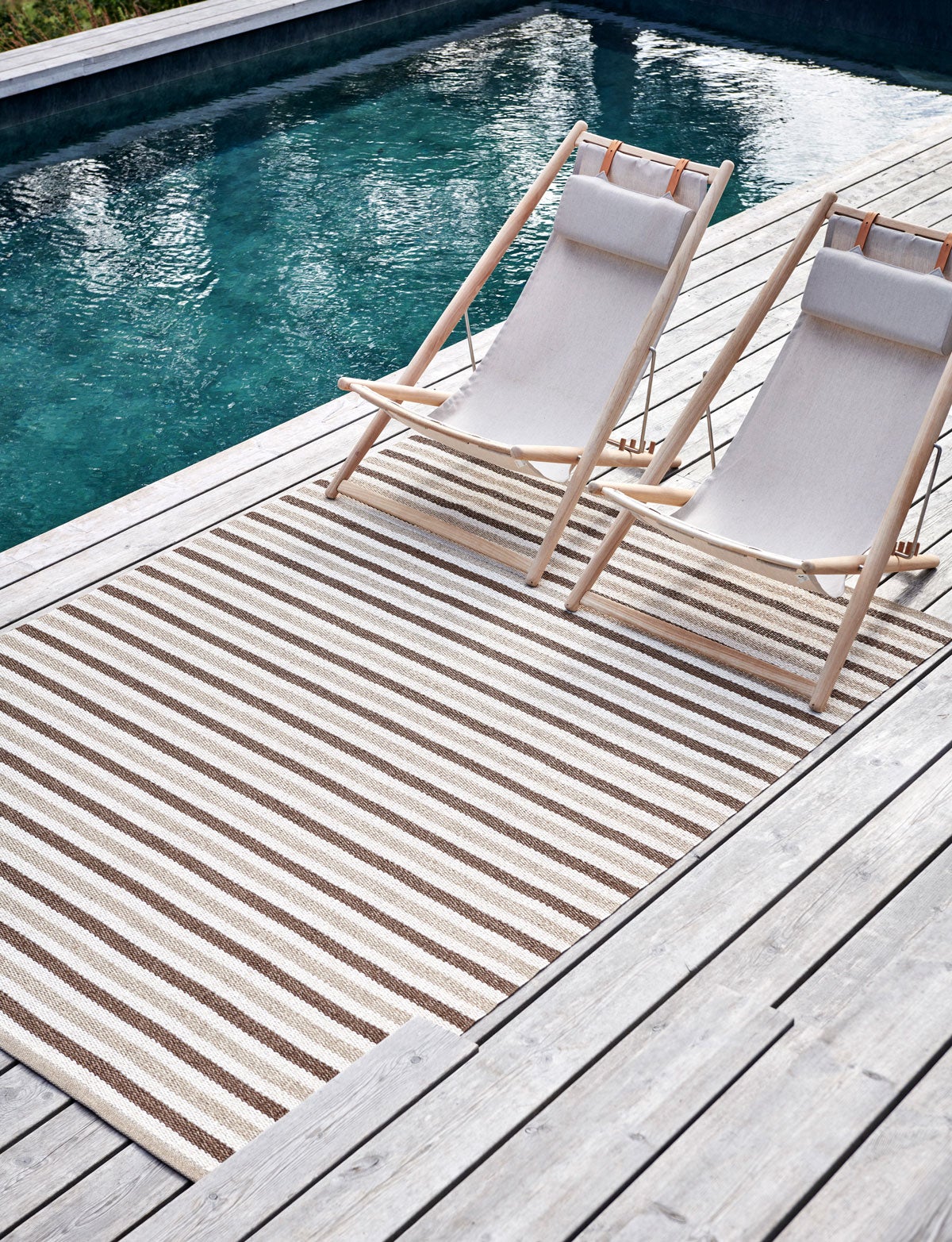 Teo Matta Brown intill pool med två solstolar