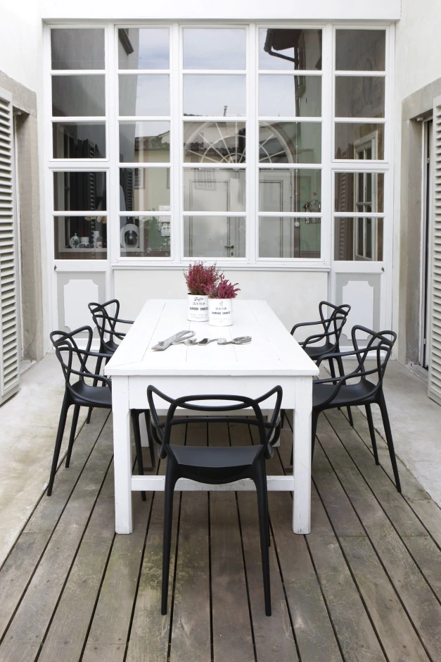 Masteras Stolar o svart runt ett vitt bord på en uteplats vid medelhavet. 