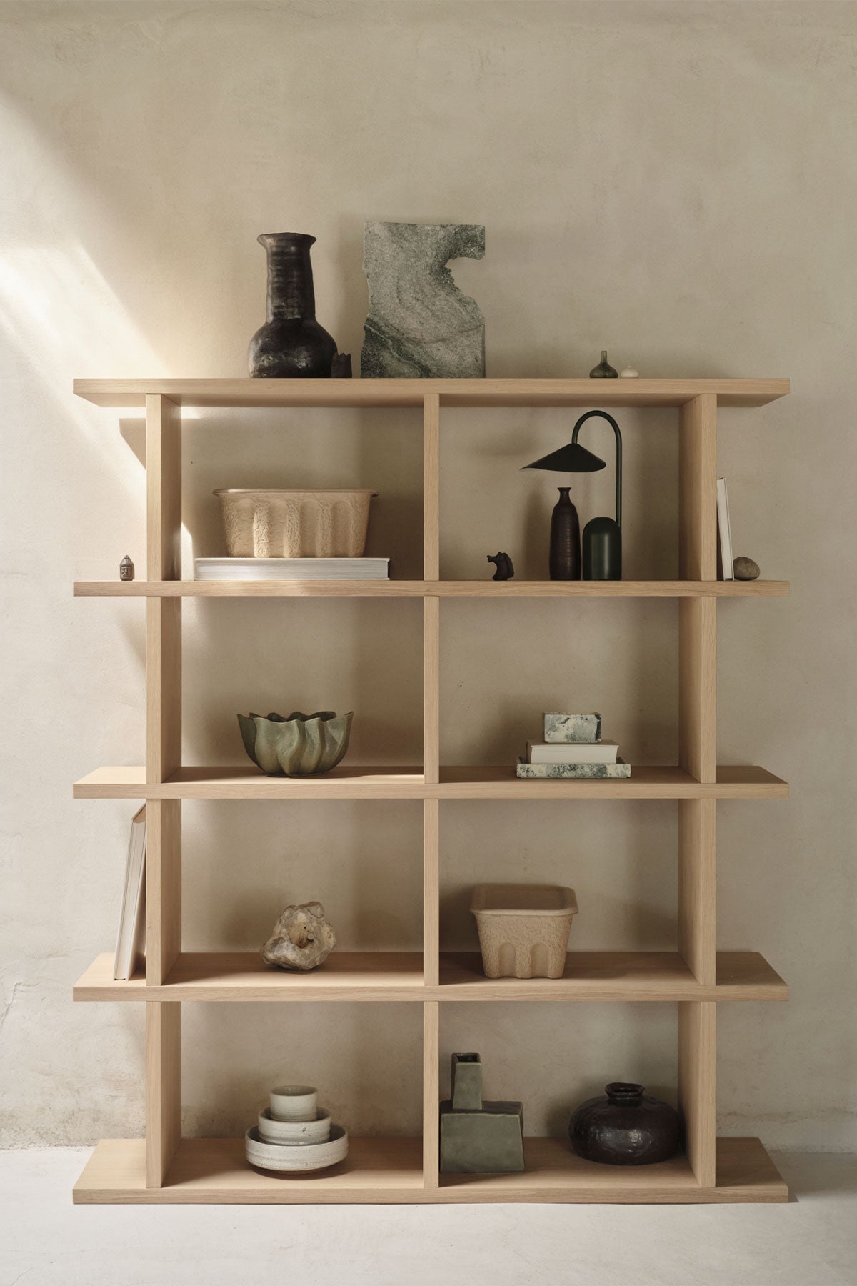 Kona 2x4 i färgen Natural ståendes mot vägg fylld med dekorationer.