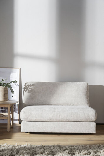 Duncan Fåtölj mot en vit vägg bredvid ett sidobord med en krukväxt