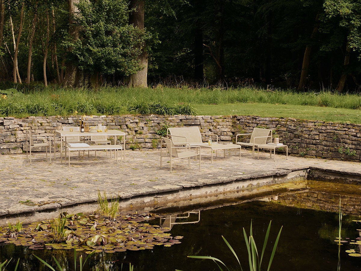 Loungeserien Dapple i färgen Cashmere som står på en stenig uteplats bredvid en damm