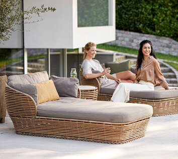 Två tjejer hänger i Basket Dagbädd på en uteplats en varm sommardag. 