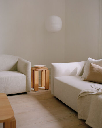 Atlas Pall Naturoljad Ek bredvid en soffa i ljust tyg