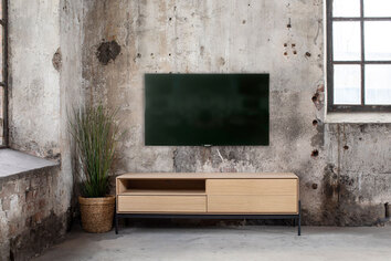 Ale Mediabänk i industriell miljö under en vägghängd TV