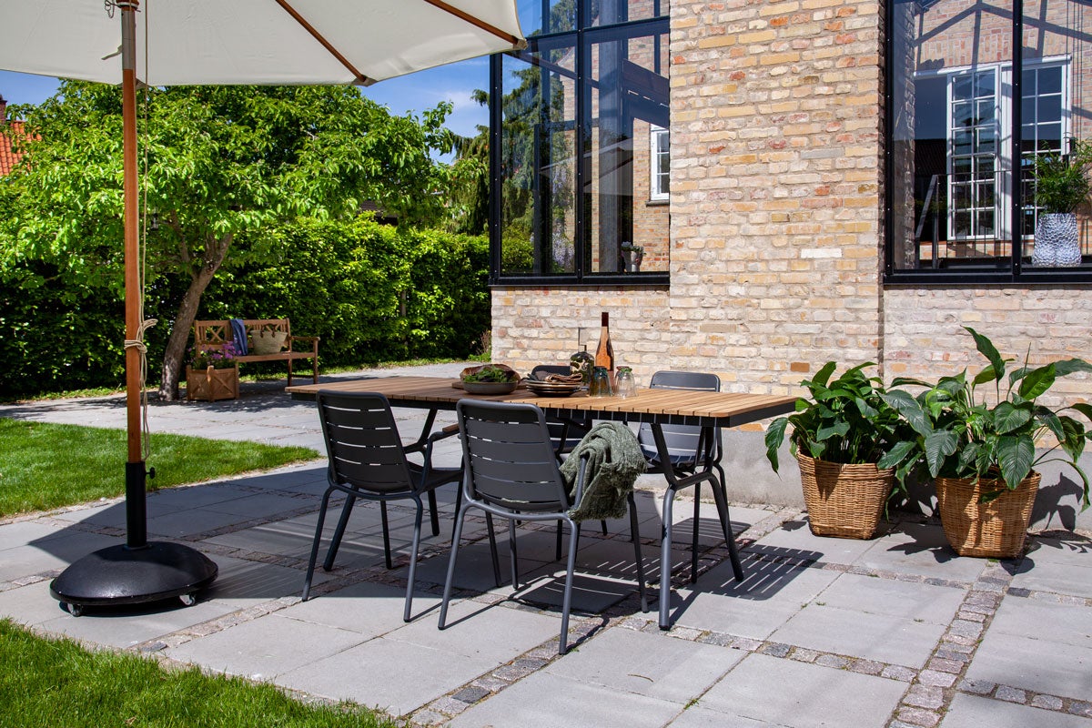 Parc Karmstol runt Parc Trädgårdsbord i solig utomhusmiljö under ett parasoll