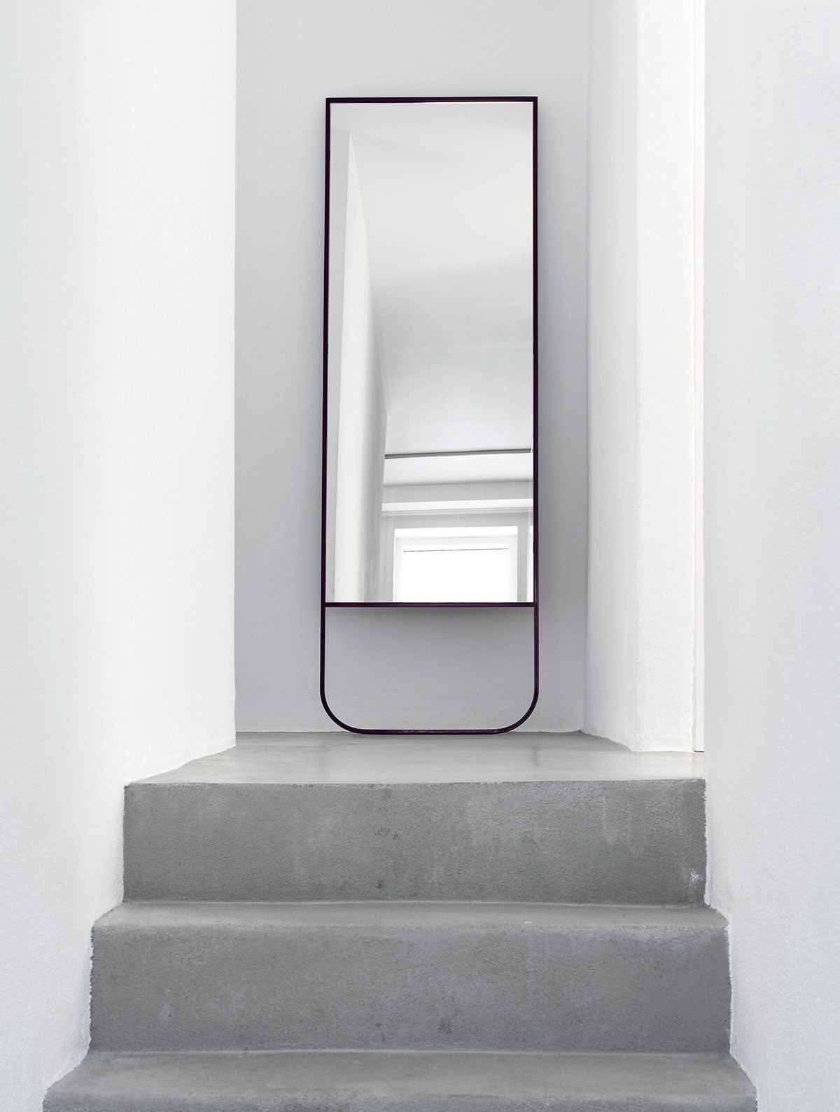 Tati Spegel i färgen Char Grey på toppen av en trappa