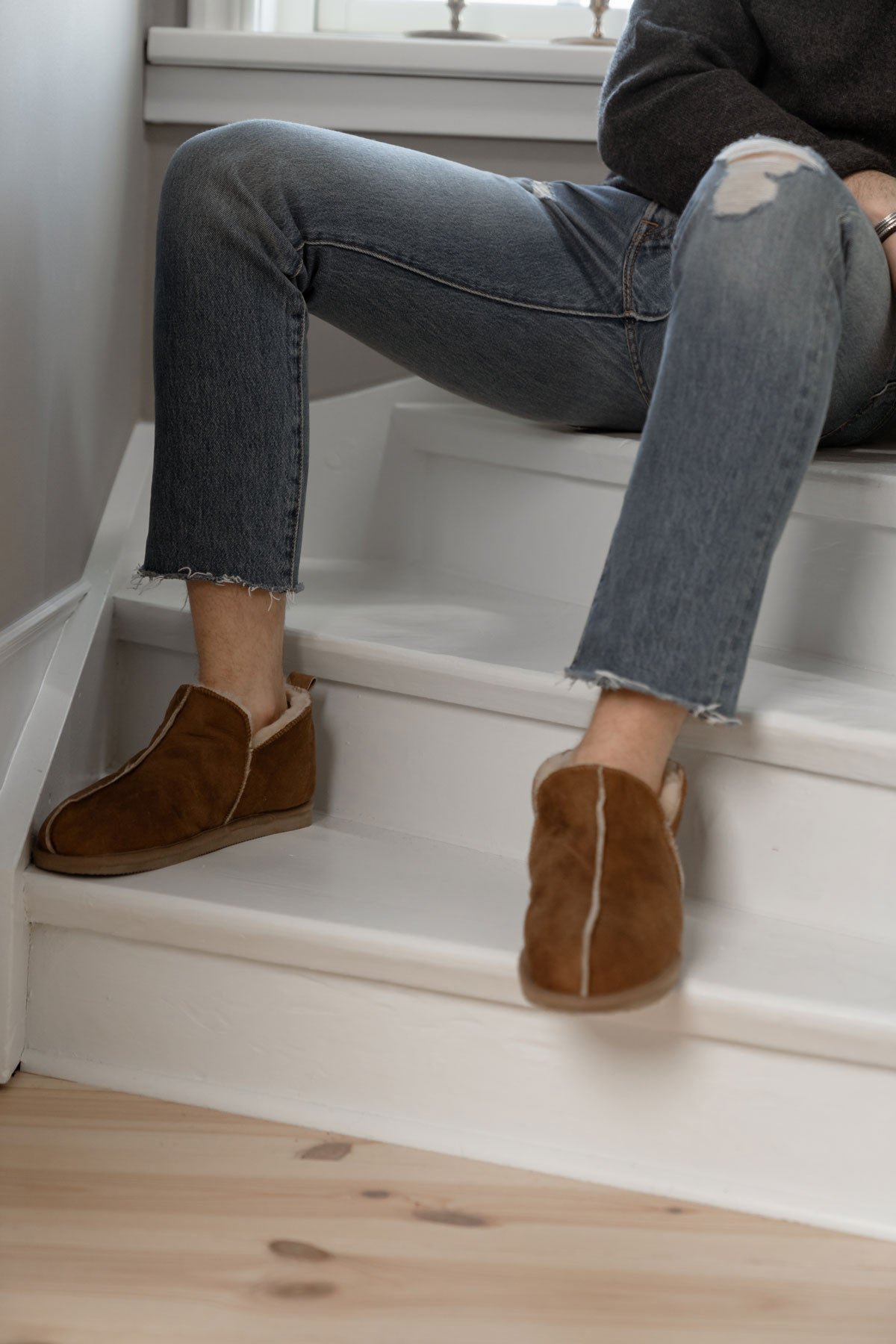 Anton Fårskinnstofflor i färgen Cognac på man som sitter lutad på en trappa