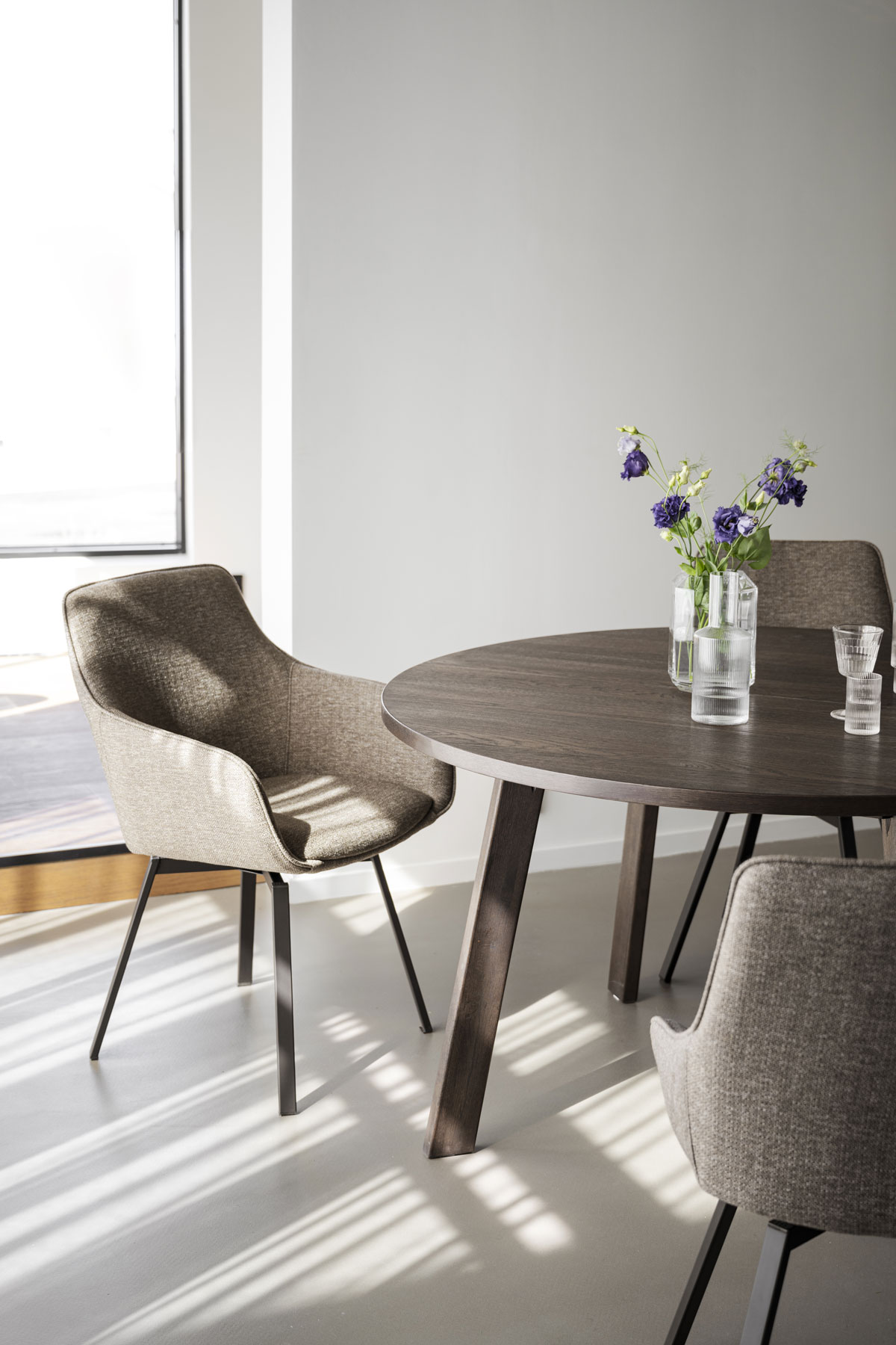 Alison Karmstol Mörkbeige vid runt matbord i soligt rum