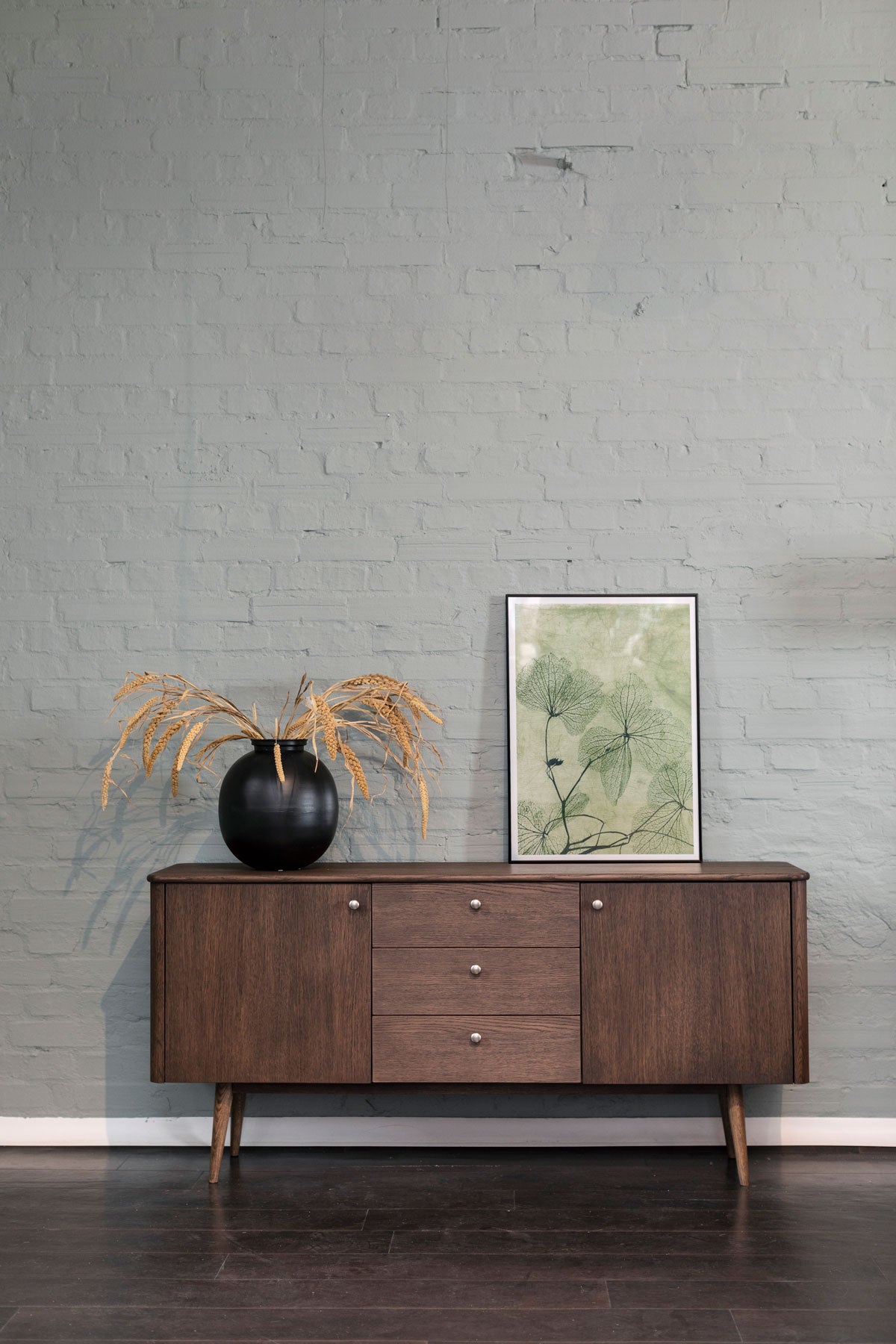 Löderup Sideboard dekorerad med en vas och en tavla med grönt, grafiskt motiv