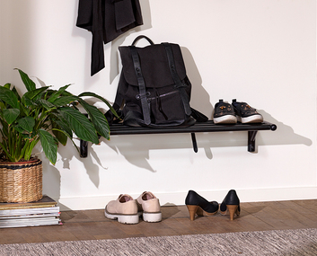 Milford Skohylla Svart på vägg i hall med flera par skor och en svart ryggsäck