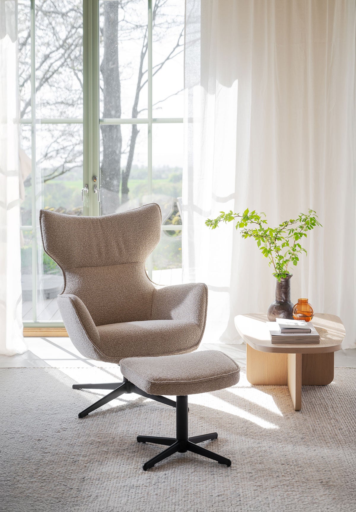 Jenkins Fåtölj och fotpall framför ett fönster med skira gardiner