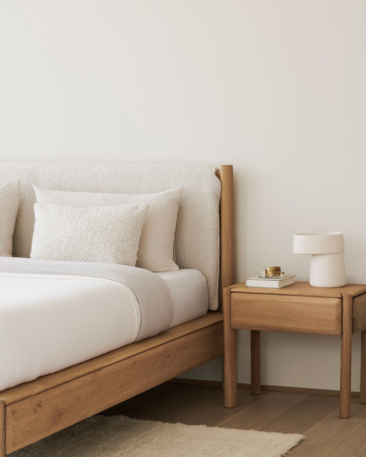 PI Sängram 160x200 i tyget Cloud i ett sovrum med ett sängbord. Sängen är bäddad med vita sängkläder.