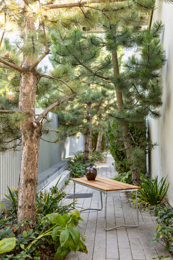 Bänk 8 Teak från Grythyttan på uteplats med tallträd