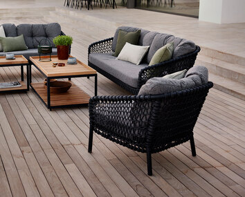 Ocean Loungefåtölj och Loungesoffa i tyget Dark Grey, stående tillsammans på ett trädäck