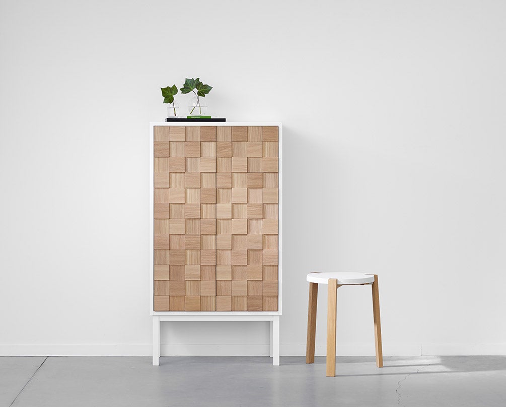 Collect 2016 Skåp Högt Vitpigmenterad Ek med två vaser med löv bredvid en pall