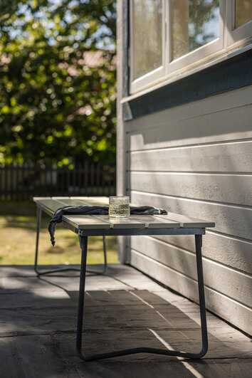 Bänk 9 i vitlackad ek från Grythyttan mot solig husfasad