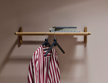 Miss Holly Hatthylla i hall med två galgar och dekorativa böcker