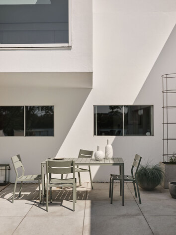 Bigby Matbord 144x74 Grön med stolar mot vit husfasad utomhus