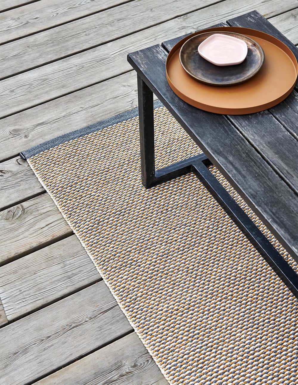 pappelina_effi_granit_4_creative.jpg Pappelinas Matta Effi i färgen granit under en svart bänk