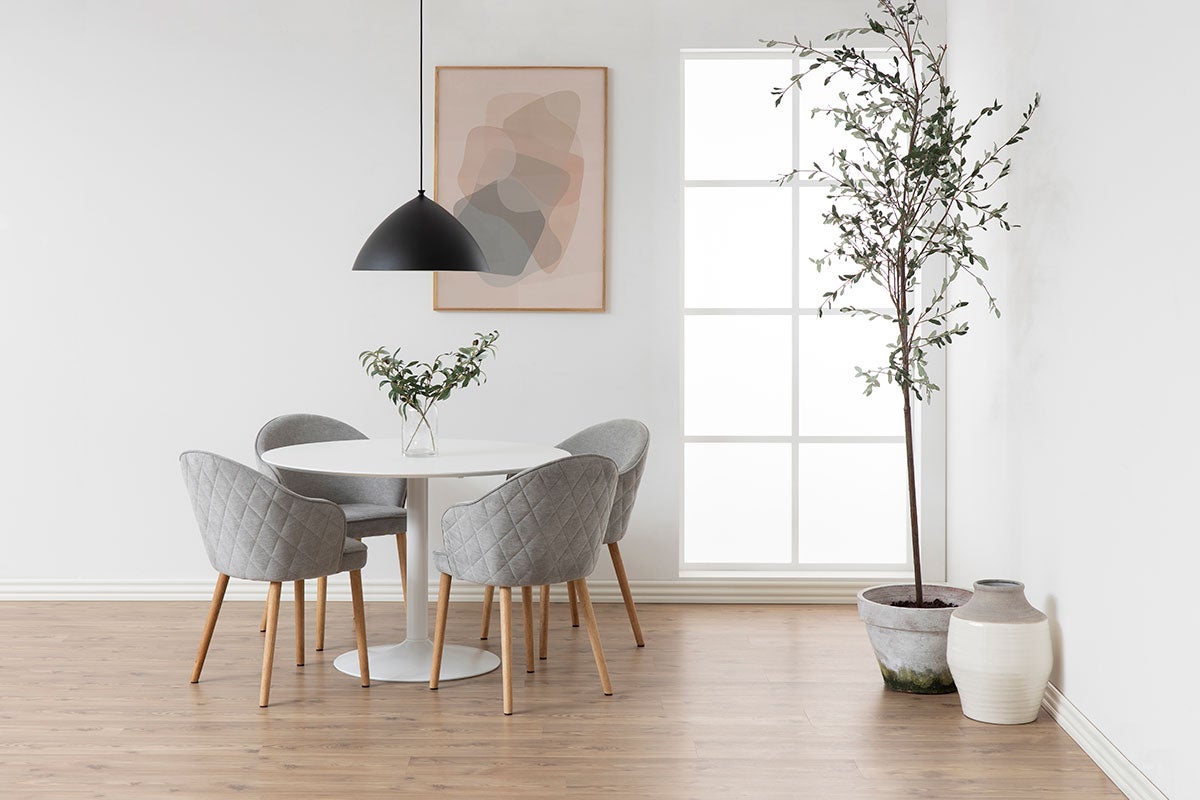 Ibiza Matbord i vit MDF med fyra matstolar i grått tyg som står i en ljus matsal