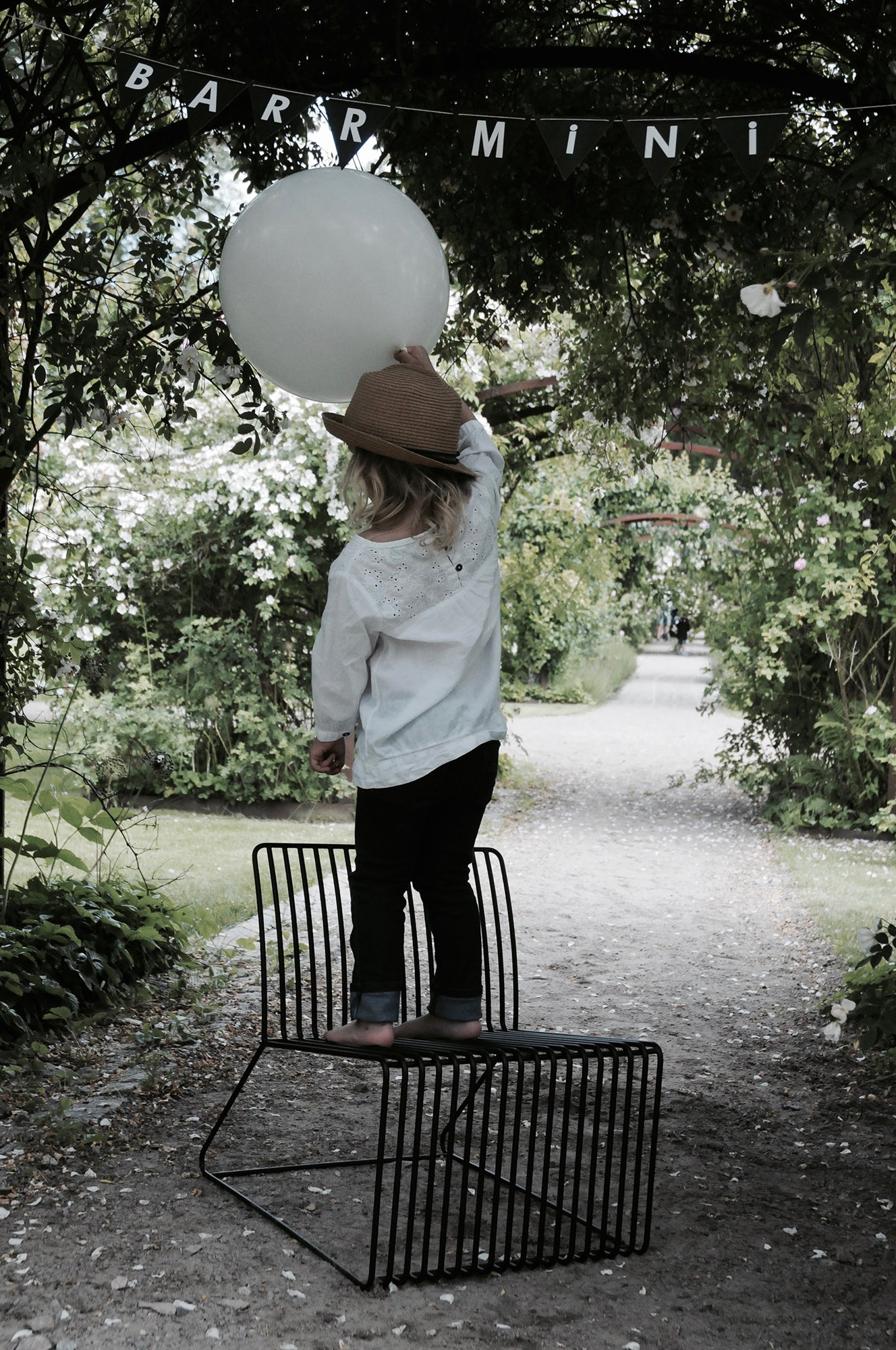 Barr Mini Loungestol Svart med ett barn som håller en ballong under en banderoll med ordet "Mini"